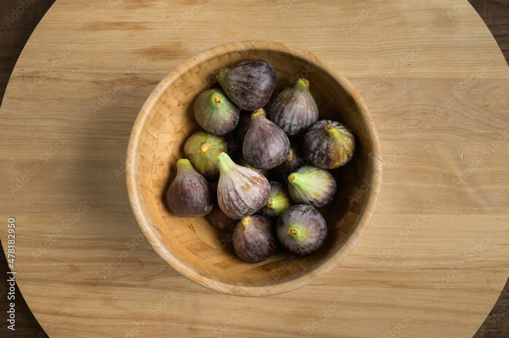 Top view figs in wooden bowl on wooden table, with copy space. High quality photo Top view figs in wooden bowl on wooden table, with copy space. High quality photo