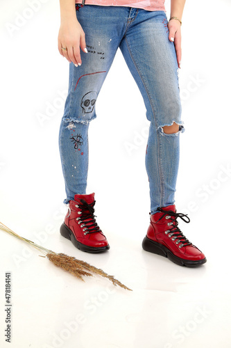 Beautiful red sneakers and woman legs in the studio on white background. Fashionable shooting of a young girl with beautiful legs