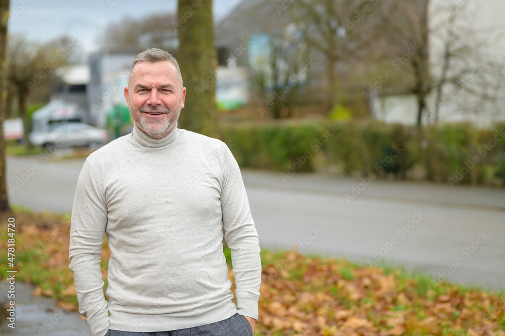 Relaxed senior man in a turtleneck standing in a street Relaxed senior man in a turtleneck standing in a street