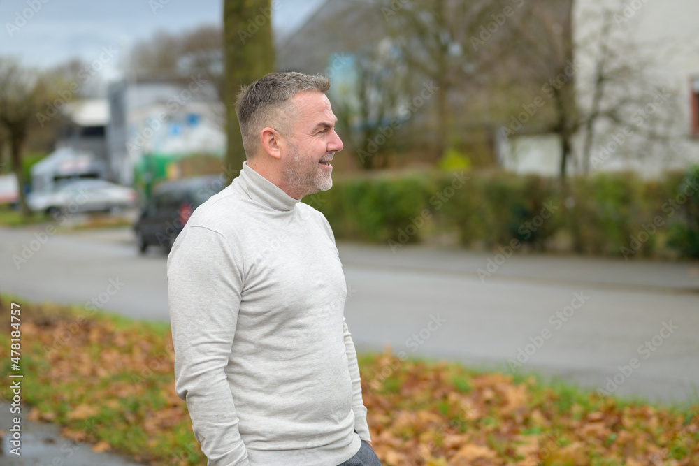 Senior man standing loking off to the side in a street Senior man standing loking off to the side in a street