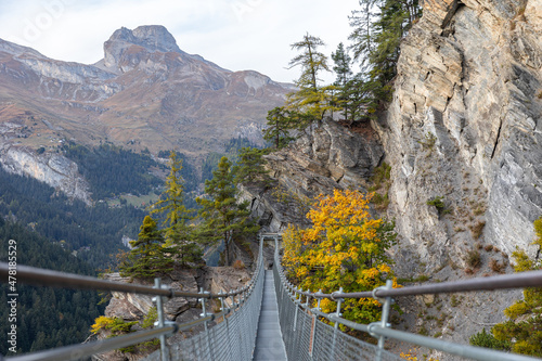 Fototapeta Naklejka Na Ścianę i Meble -  Swiss alps landscape. Hanging bridge passage in the middle of mountains. Autumn colors. Walking trail in nature. Outdoor adventure experience. Green forest valley landscape