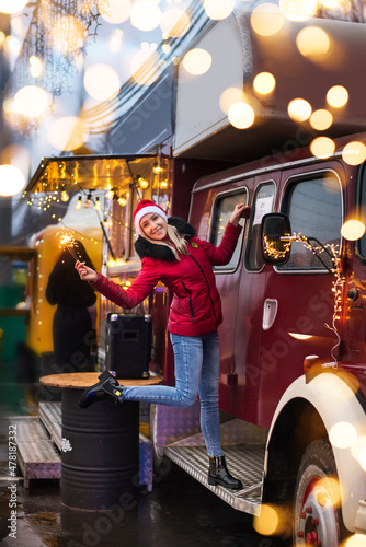 Christmas, New Year concept. Woman burning sparkler by Christmas city street fair.