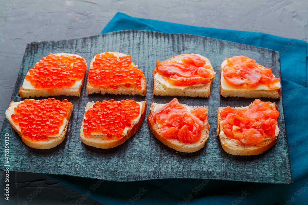 Bruschetta with trout and red caviar on a black board. Bruschetta with trout and red caviar on a black board.