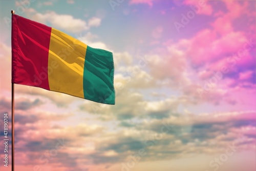 Fluttering Guinea flag mockup with the space for your content on colorful cloudy sky background.