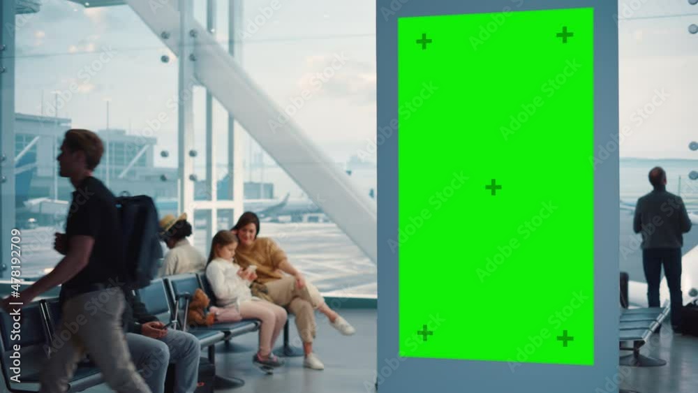 Airport Terminal: Green Screen Advertising Billboard, Arrival Display with Chroma Key, Mock-up AD Space. Backgrond: Diverse Crowd of People Wait for their Flights in Boarding Lounge of Airline Hub