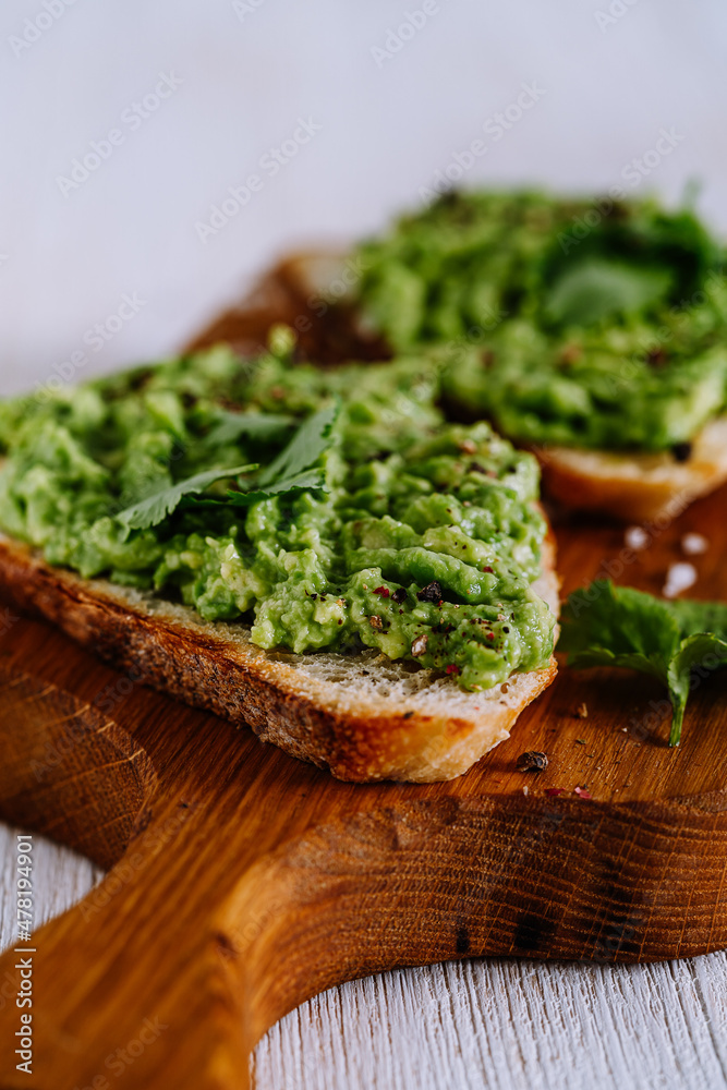 Mashed avocado on toasted bread on cutting board served with cilantro Mashed avocado on toasted bread on cutting board served with cilantro