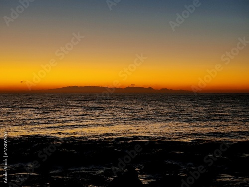 Isla en el horizonte y cielo anaranjado