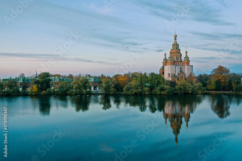 Olga's Pond and the Cathedral of Peter and Paul in Peterhof at sunset, the reflection of the sky and trees in the water, a church with domes, a photo for a postcard