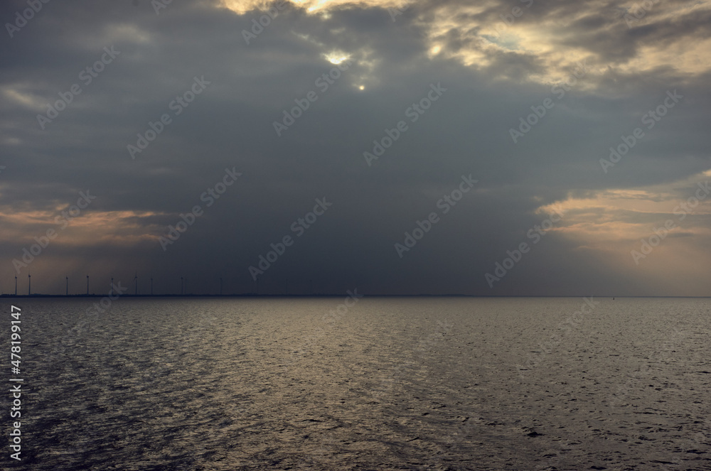 Wind turbine - the sky and the sea, the sun breaks through the clouds, cargo ship at sea Wind turbine - the sky and the sea, the sun breaks through the clouds, cargo ship at sea