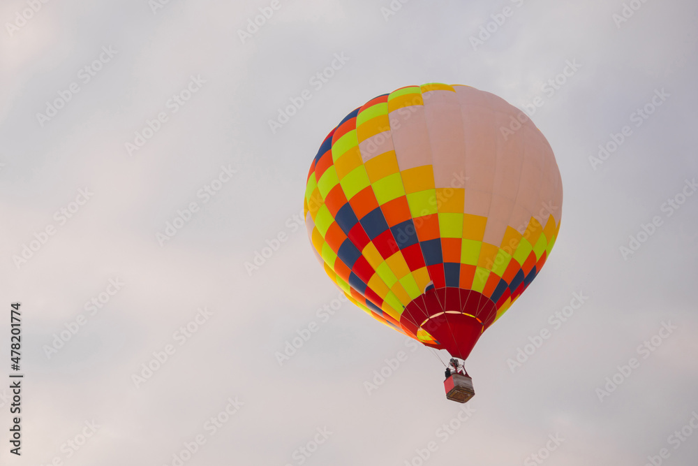 Obraz premium Colorful hot air balloon flying against grey sky at Winter aerostat festival. Freedom, sport, aircraft concept