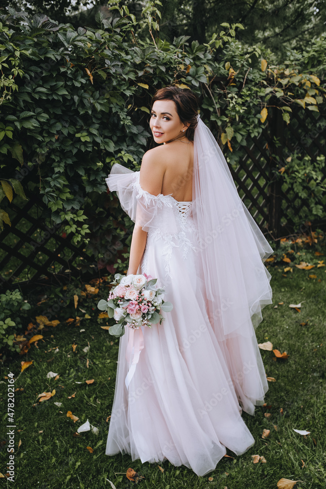 Wedding portrait of a beautiful brunette girl with a bouquet in her hands on the background of green nature ivy foliage. Wedding portrait of a beautiful brunette girl with a bouquet in her hands on the background of green nature ivy foliage.