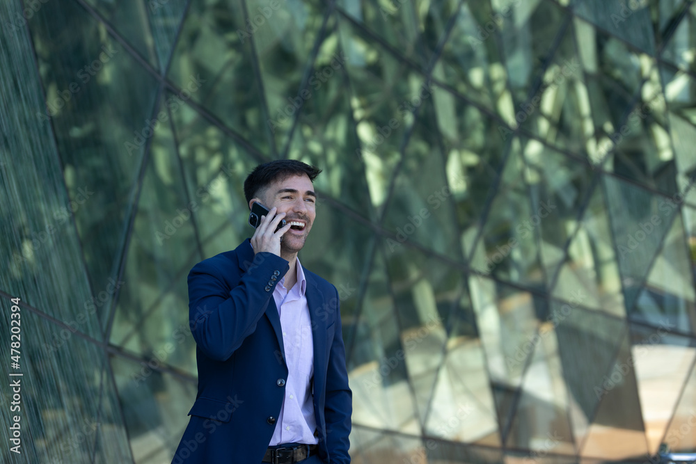 Business man smiling on phone call. Weating a blue suit in a modern area. Business man loughter Business man smiling on phone call. Weating a blue suit in a modern area. Business man loughter