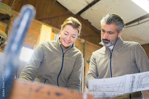 male and female workers looking at plans in workshop photo