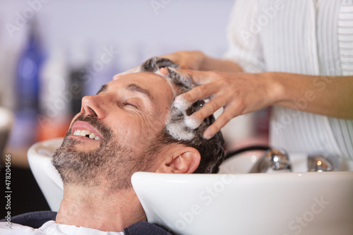 hairdresser washing hair to her handsome client