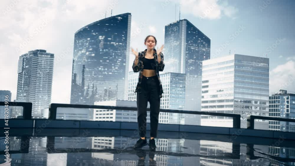 Stylish Young Professional Female Dancer Performing an Internet Meme Dance Routine in Front of Big Led Wall Screen with Modern City Skyline with Office Skyscrapers in Studio Environment. Stylish Young Professional Female Dancer Performing an Internet Meme Dance Routine in Front of Big Led Wall Screen with Modern City Skyline with Office Skyscrapers in Studio Environment.