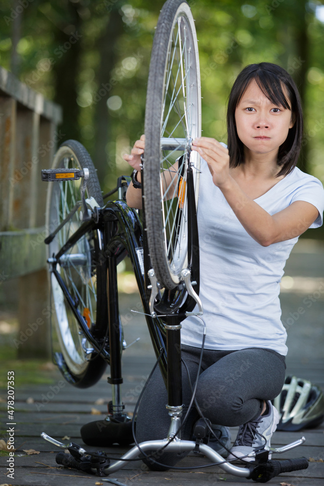 Obraz premium upset woman checking bicycle chain in the park
