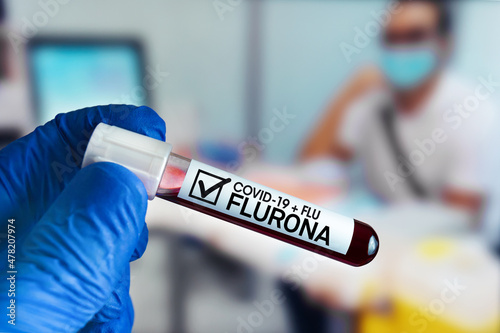 doctor holding blood sample from a patient with positive to Flurona Flu and covid-19. doctor with a tube of blood sample with positive result to Flurona double virus Flu + coronavirus