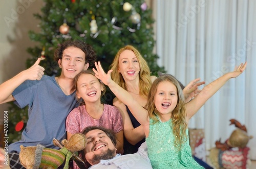 Children, two girls and a boy on the background of a Christmas tree with a blurred background in the apartment.