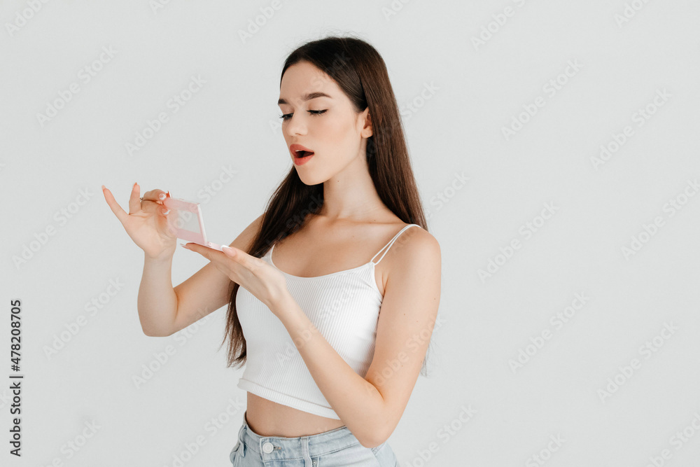 Portrait of surprized girl opening new contouring palette with bronzer, highlighter and a blush, over white color background. Receiving gifts concept