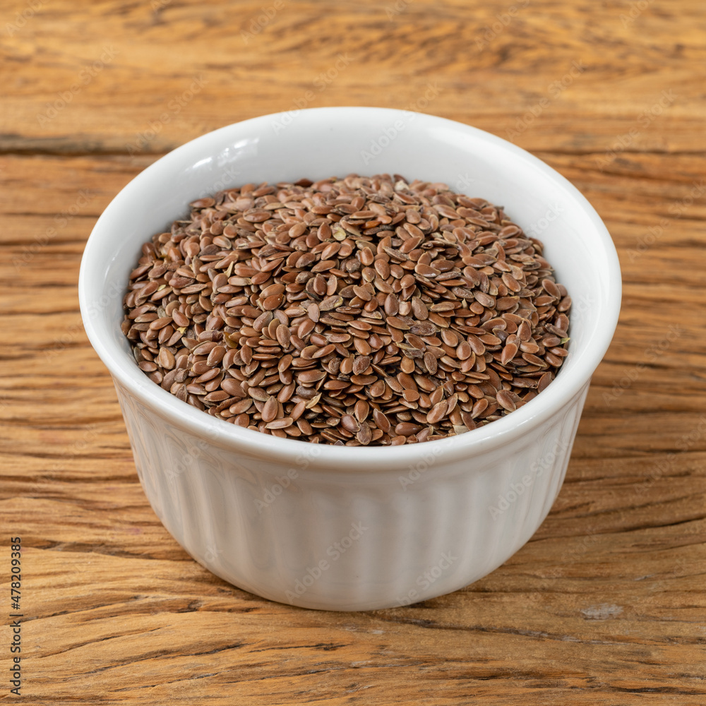 Brown linseed on a bowl over wooden table Brown linseed on a bowl over wooden table