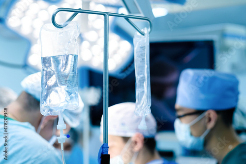 Selective focus on saline transparent plastic bag. Medical dropper in the operating room. Surgery on a blurred background.