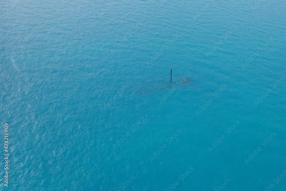 Aerial view of shipwreck in the ocean with mast sticking up