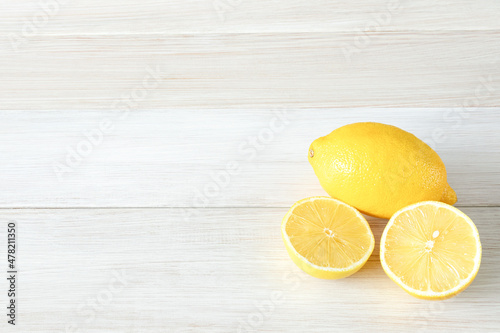 Whole and cut ripe lemons on white wooden background. Copy space