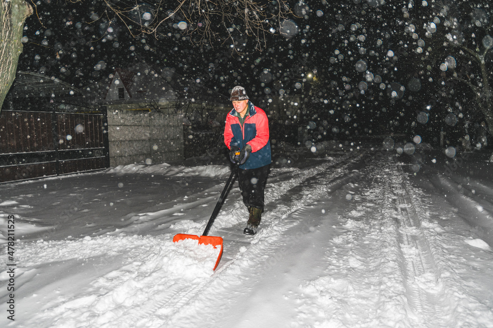 Elderly man with a shovel in his hands clears the street after a heavy snowfall. Man at seasonal work