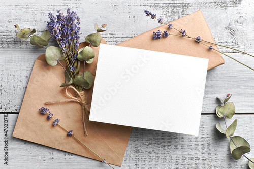 Wedding invitation or greeting card mockup with lavender and eucalyptus flowers on wooden background