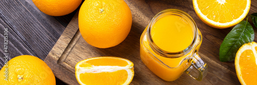 Banner Fresh orange juice in a glass on a wooden background. Fresh Orange fruits with green leaves. Healthy vegan food. Vitamins food.Ripe oranges.Flat lay.
