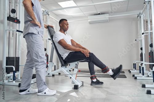 Concentrated young man working out with kinesiologist
