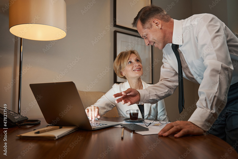 Business colleagues discussing something, working on laptop in hotel room Business colleagues discussing something, working on laptop in hotel room