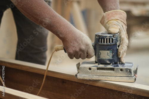 Worker hands polishing wood with machine