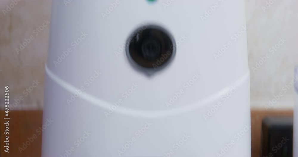 Modern white plastic automatic feeder for pets standing on orange tiled floor in kitchen against plaster wall extreme closeup Modern white plastic automatic feeder for pets standing on orange tiled floor in kitchen against plaster wall extreme closeup