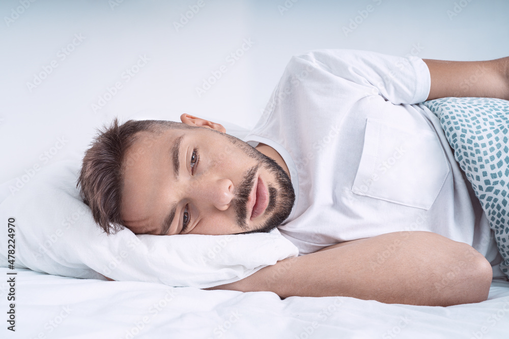 Stressed and depressed man lying in the bed. Man feeling bad, desperate and helpless Stressed and depressed man lying in the bed. Man feeling bad, desperate and helpless