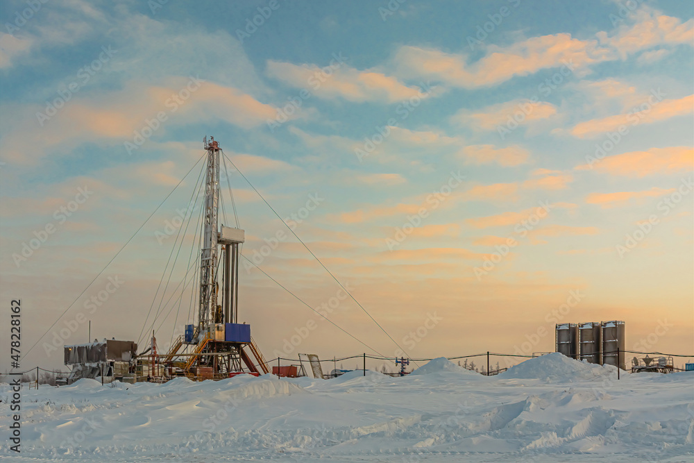 Drilling wells in the winter at an oil and gas field in the Arctic. Polar day with textured beautiful sky. Steam puffs for heating equipment Drilling wells in the winter at an oil and gas field in the Arctic. Polar day with textured beautiful sky. Steam puffs for heating equipment