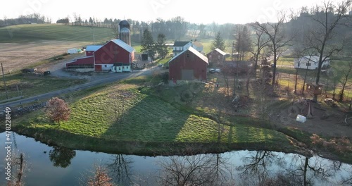 Aerial reveal of American family farm with creek stream river flowing through field. Rural farmscape. photo