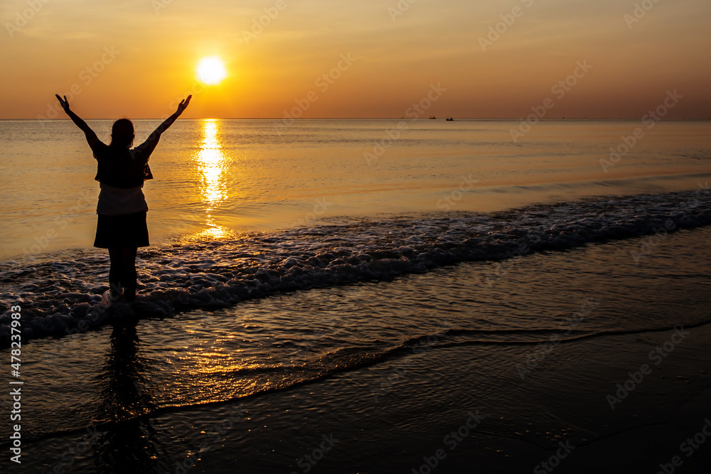 Silhouettes  of Woman raise hands up to the sunset sky  praise and worship God against the sun  at the beach with copy space for your text, Christian praise and worship concept .