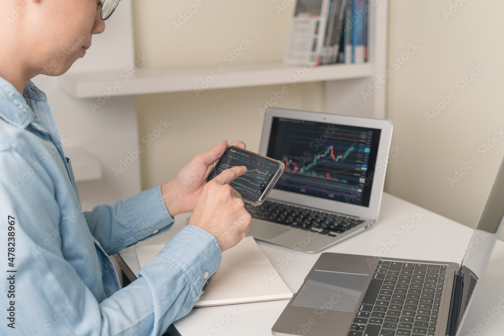 Trader man using, pointing smartphone, laptop with technical price of stock market, Cryptocurrency graph chart for trading, investing on stock market, Cryptocurrency as Bitcoin on online platform. Trader man using, pointing smartphone, laptop with technical price of stock market, Cryptocurrency graph chart for trading, investing on stock market, Cryptocurrency as Bitcoin on online platform.