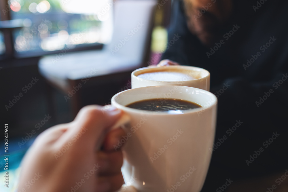 Closeup image of a couple people clinking coffee cups together in cafe Closeup image of a couple people clinking coffee cups together in cafe