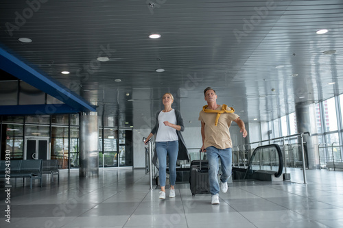 Two airline passengers rushing along the airport terminal