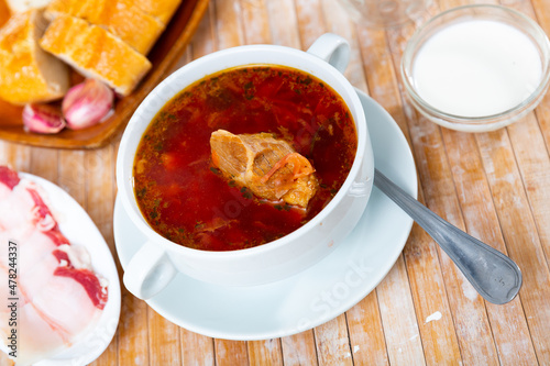 Appetizing Russian dish borscht served with sour cream, bread and salo in a cafe