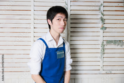 白シャツに青いエプロンをつけた日本人男性