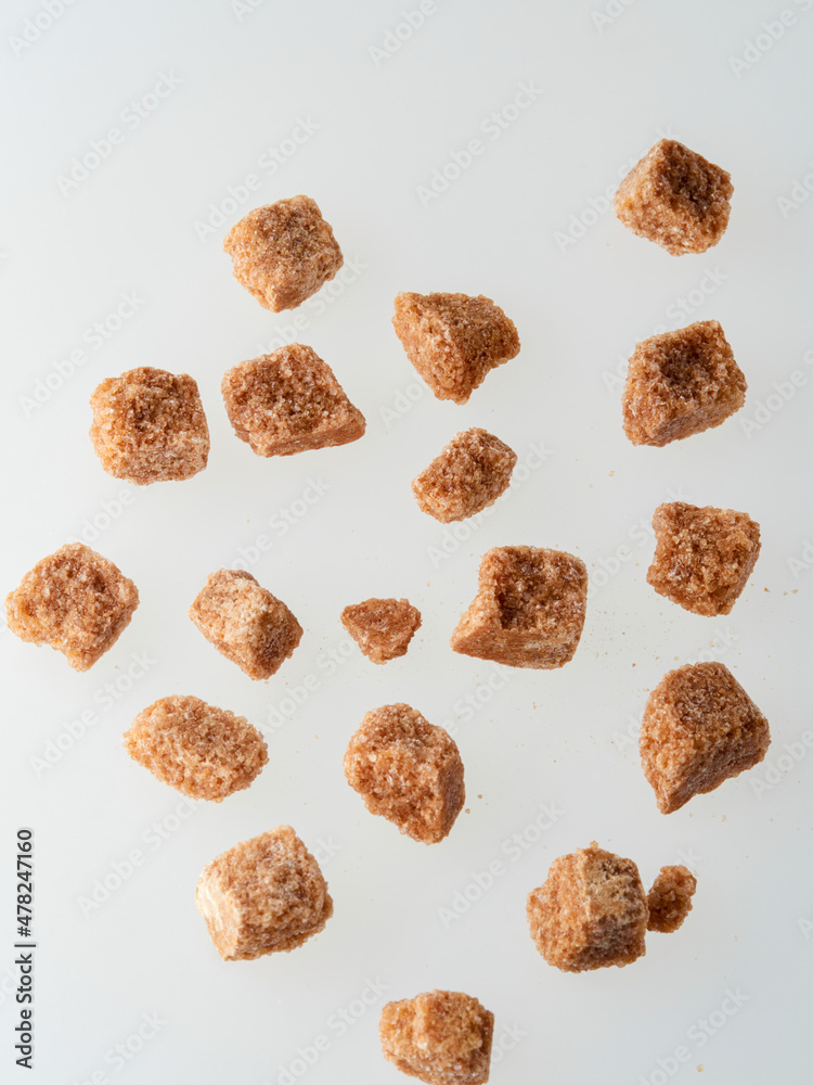 Pile of brown granulated sugar and sugar cubes isolated on white Pile of brown granulated sugar and sugar cubes isolated on white