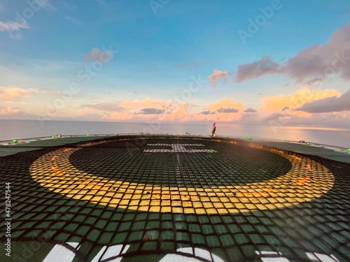 Helideck of construction support vessel over the sea under sunrise
