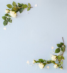 Frame from white roses flowers on light blue background. Artificial white roses and pearl beads in corner shape. Decorated background with empty place for text
