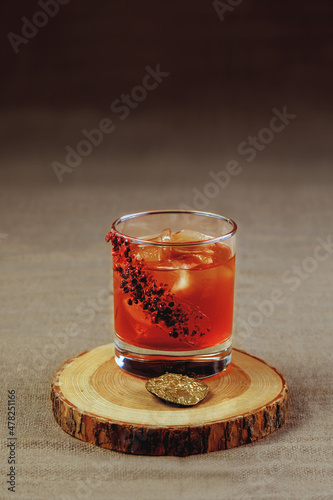 A bright cocktail with ice cubes on a wooden stand. Cooling alcoholic beverage.
