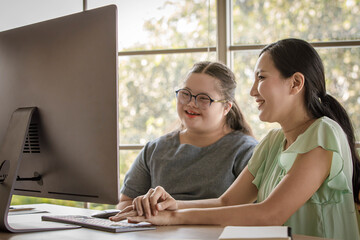 Portrait shot of Asian happy lovely young chubby down syndrome autistic autism little daughter and mother smiling look at camera while learning online via computer. Teacher teaching lesson to student