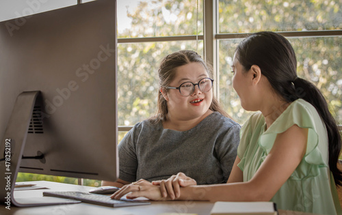 Foto Portrait shot of Asian happy lovely young chubby down syndrome autistic autism little daughter and mother smiling look at camera while learning online via computer
