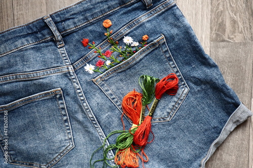 Creative DIY project, hand embroidery at home on jeans, creative hobby, clothes recycle, floral embroidery design, colorful threads, embroidery needle photo